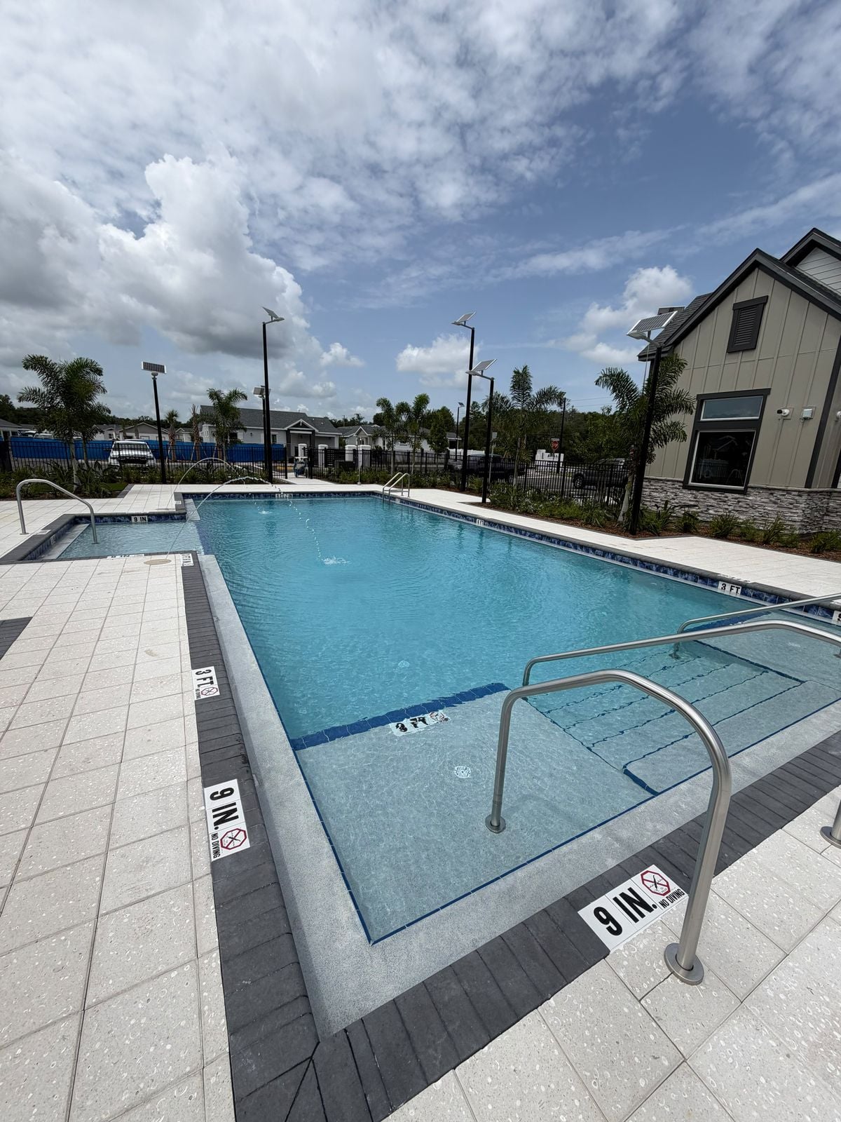 Clear blue community pool with a tanning ledge, kept clean and swim-ready in the Orlando area