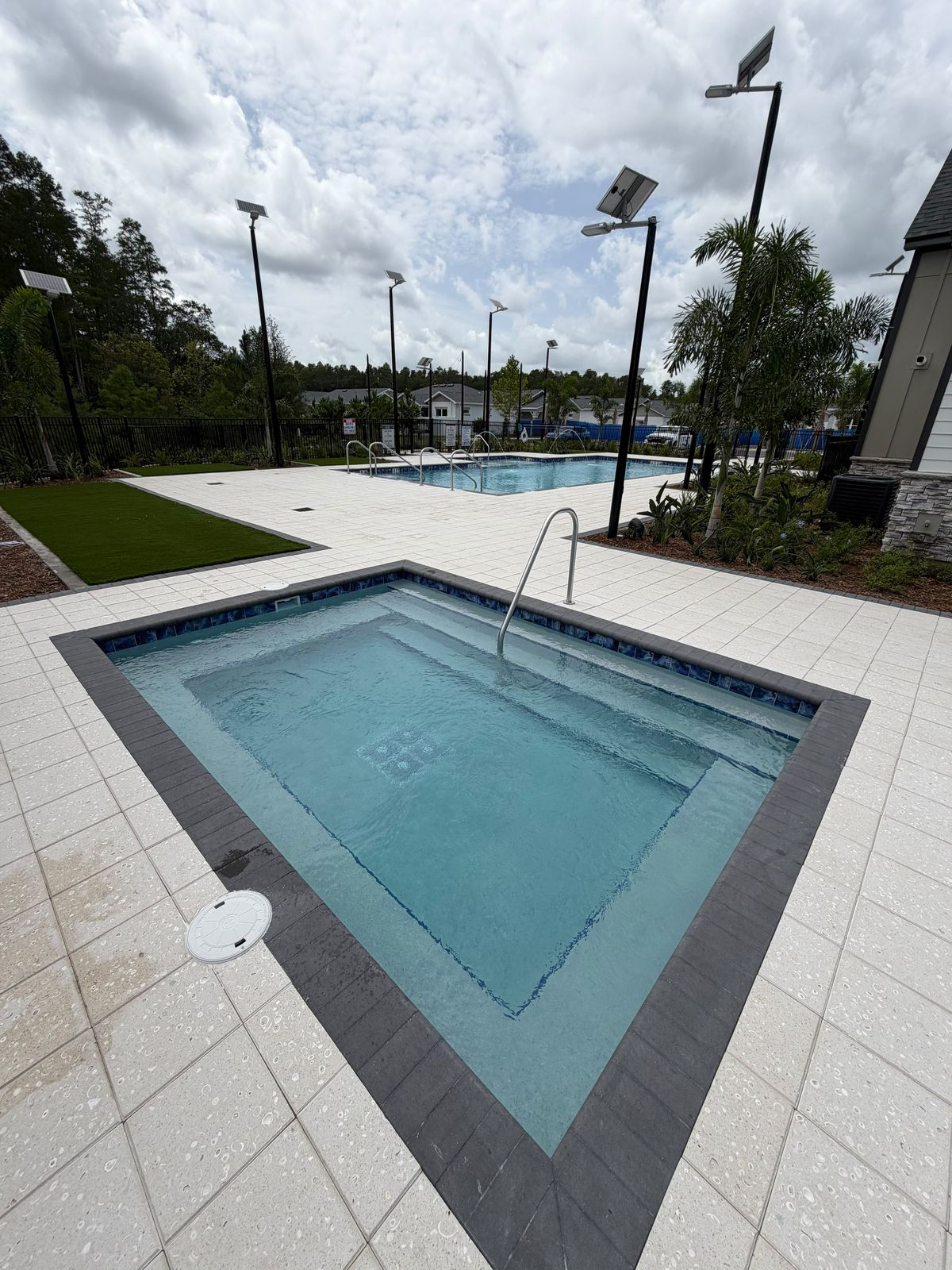 Spillover spa and hot tub next to a resort-style community pool, serviced and sparkling clean